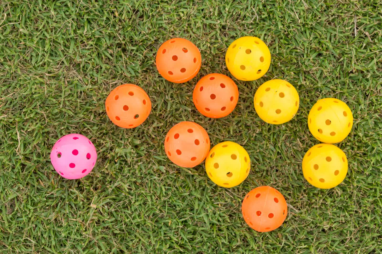 Colorful pickleballs scattered on grass